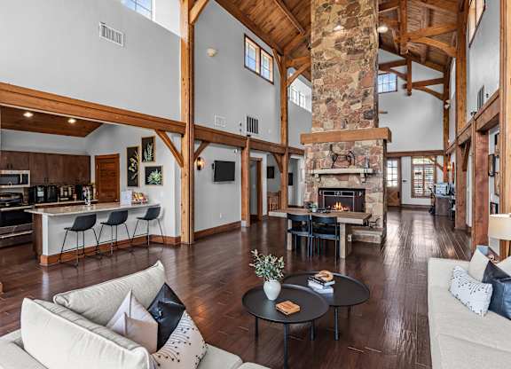 A large open living room with a stone fireplace and a dining area with a bar.
