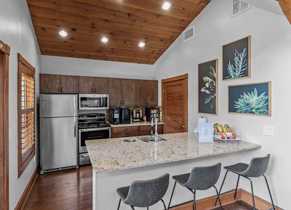 A kitchen with a refrigerator, oven, and sink.