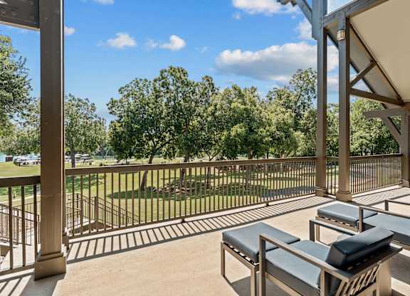 A patio with a table and chairs overlooking a grassy area.