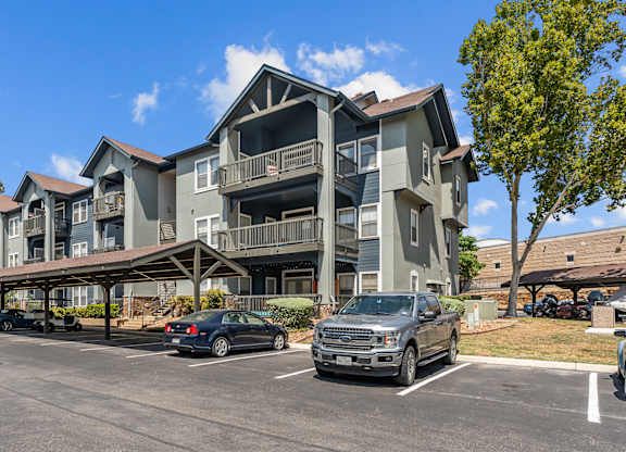 A large apartment complex with a parking lot in front.