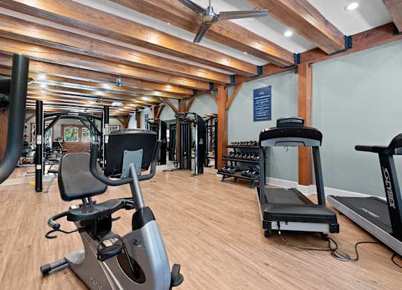 A gym with a wooden floor and a variety of exercise equipment.