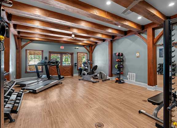 A spacious home gym with wooden floors and a variety of exercise equipment.
