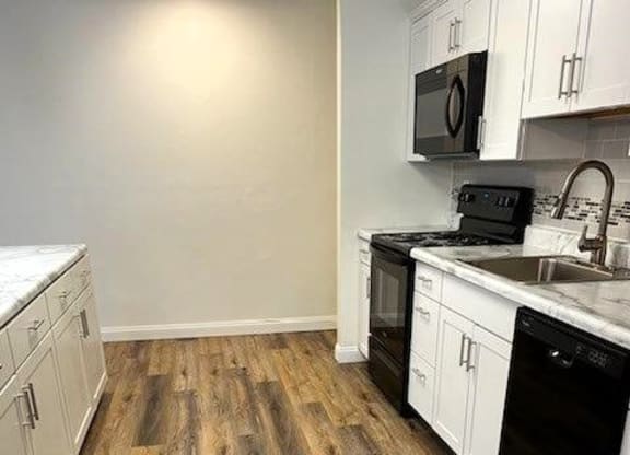 a kitchen with white cabinets and a wooden floor