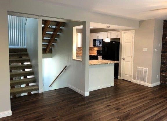 a living room with a staircase and a kitchen