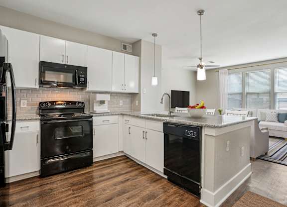 A modern kitchen with white cabinets and black appliances.