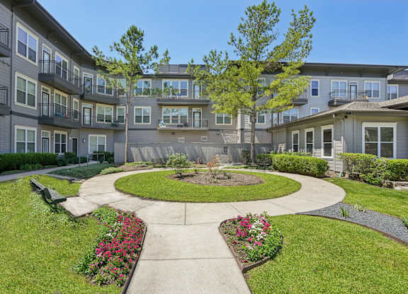 A courtyard with a circular walkway and a bench is surrounded by apartment buildings.