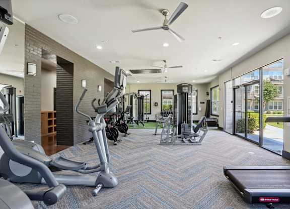 Bright fitness center with cardio equipment and large windows at Highline Urban Lofts Apartments, Cypress, Texas
