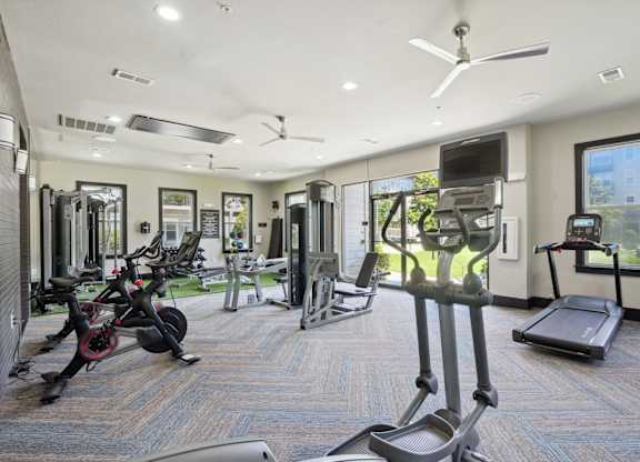 Spacious gym with exercise machines and ceiling fans at Highline Urban Lofts Apartments, Cypress
