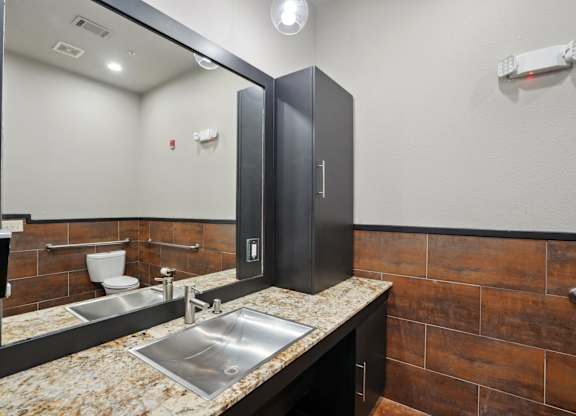 Modern restroom with granite countertops and wood tile accents at Highline Urban Lofts Apartments, Cypress, Texas
