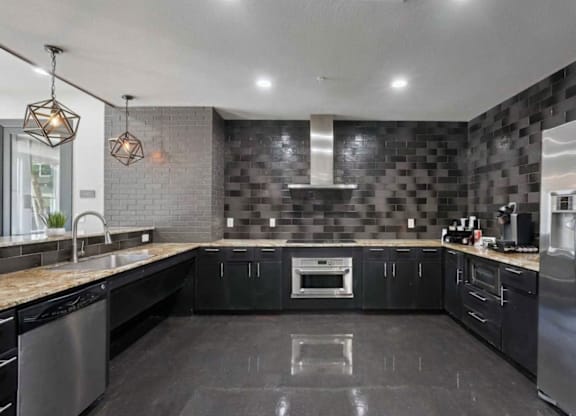 A modern kitchen with black cabinets and a stainless steel refrigerator.