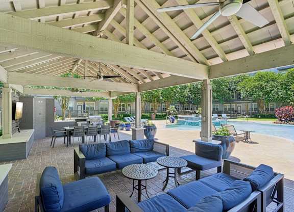 Covered poolside pavilion with blue outdoor furniture and dining area at Highline Urban Lofts Apartments, Cypress, 77429