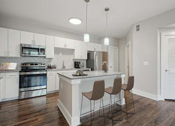 White kitchen with island seating and pendant lighting at Highline Urban Lofts Apartments, Cypress