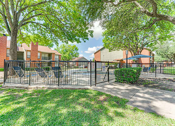 A black metal fence surrounds a green lawn at Bardin Oaks Apartments, Arlington