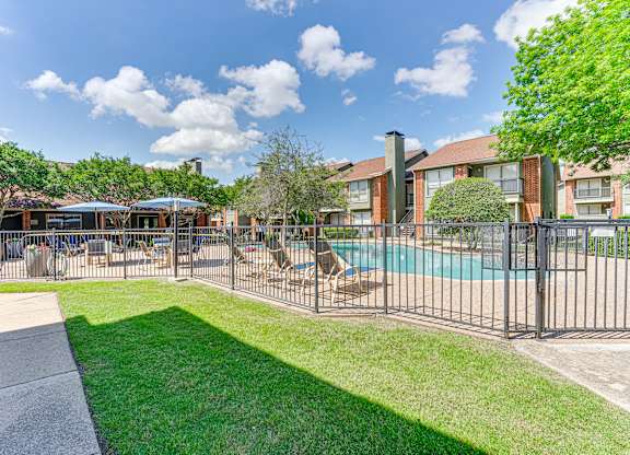 A sunny day at the poolside with a building in the background at Bardin Oaks Apartments, Arlington, TX