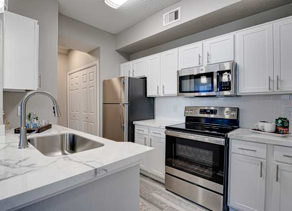 Modern kitchen with white cabinets and marble countertops at Carmel Creekside Apartments, Fort Worth, 76137