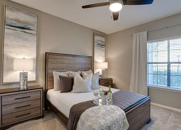 Bedroom with wood furniture and ceiling fan at Carmel Creekside Apartments, Fort Worth, Texas