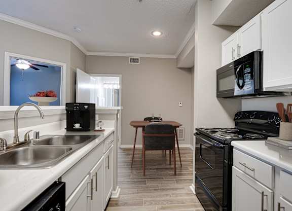 Modern kitchen with white cabinets and black appliances at Carmel Creekside Apartments, Texas, 76137