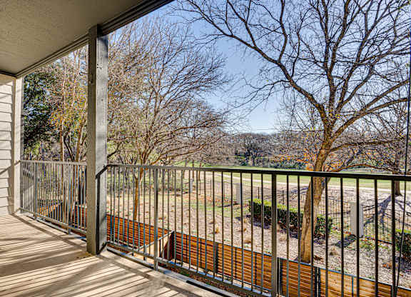 Balcony overlooking green space and bare trees at Carmel Creekside Apartments, Texas