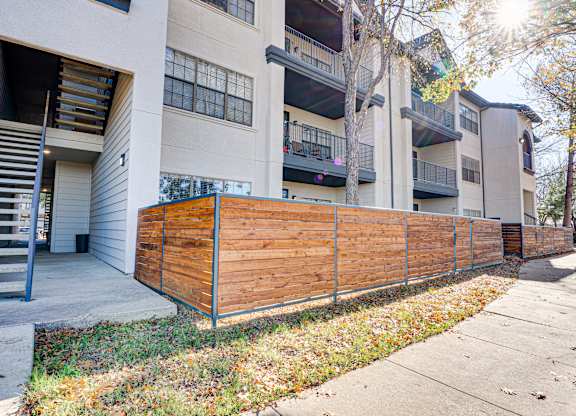 Apartment building exterior with wood privacy fence at Carmel Creekside Apartments, Texas, 76137