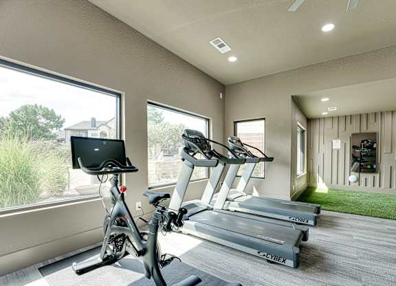 Fitness center with cardio equipment and turf area at Carmel Creekside Apartments, Fort Worth, TX 76137
