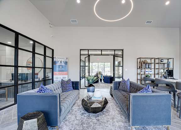 Clubhouse lounge with blue sofas and decorative shelving at Carmel Creekside Apartments, Texas