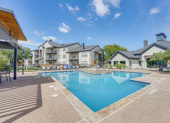 Resort style pool with lounge chairs and clubhouse at Carmel Creekside Apartments, Fort Worth
