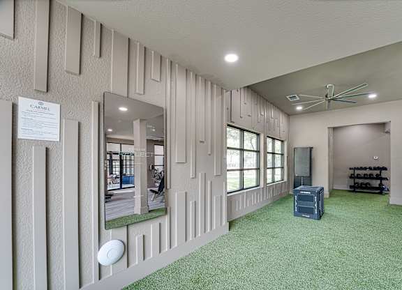 Fitness studio with turf flooring and mirrored wall at Carmel Creekside Apartments, Fort Worth, Texas