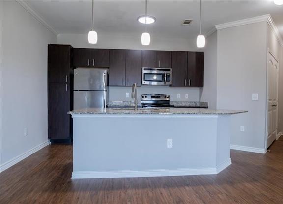 A kitchen with a white island and dark brown cabinets.