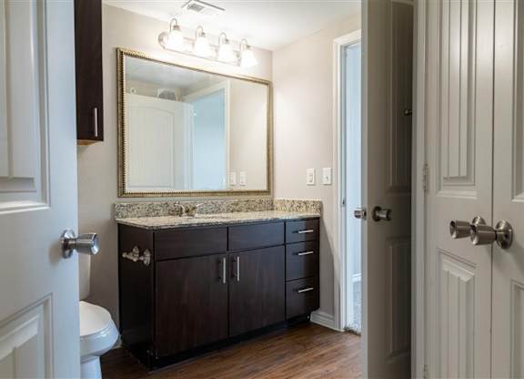 A bathroom with a marble countertop and a large mirror.