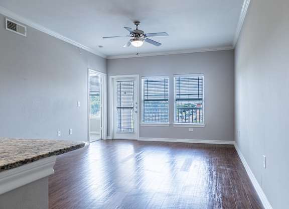 A room with a ceiling fan and sliding glass doors.