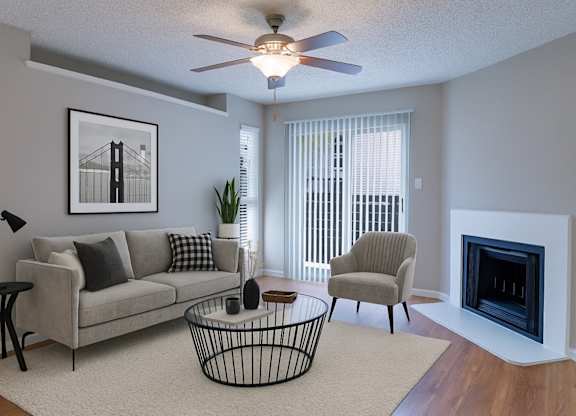 A living room with a grey couch, a chair, a coffee table, and a fireplace.