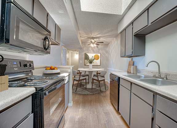 A kitchen with a stove top oven and a microwave at Indian Creek Apartments, Carrollton 75007