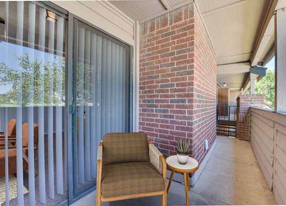 A chair and a table are on a patio at Indian Creek Apartments, Carrollton