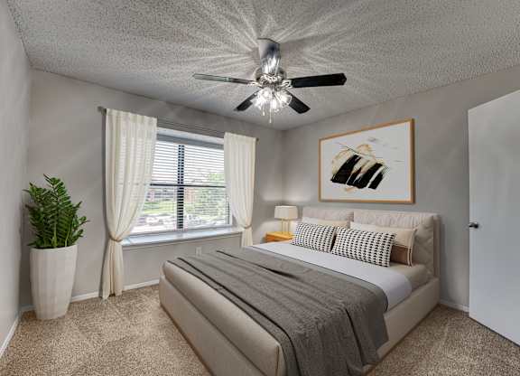 A bedroom with a bed, a ceiling fan, and a painting on the wall at Indian Creek Apartments, Texas