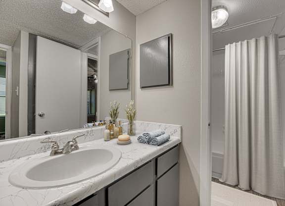 A bathroom with a white sink and a mirror at Indian Creek Apartments, Carrollton, Texas