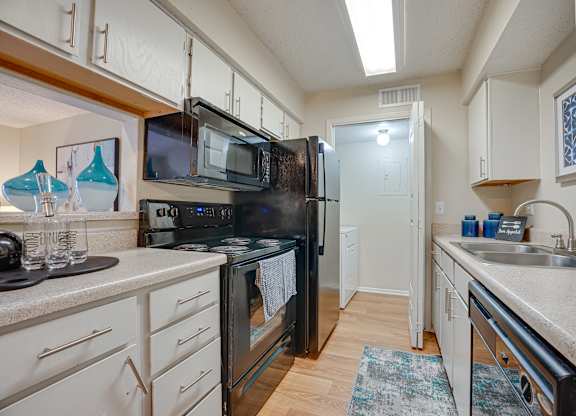 a kitchen with black appliances and white cabinets at Indian Creek Apartments, Texas