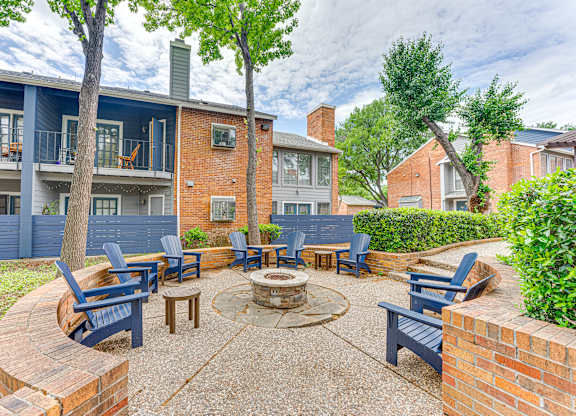 A patio with a fire pit and chairs.