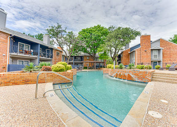 A small pool surrounded by a brick wall and steps leading to a house.