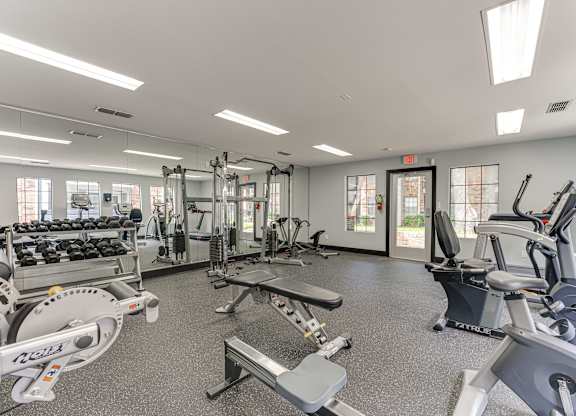 A gym with a variety of equipment including treadmills, weights, and exercise machines.