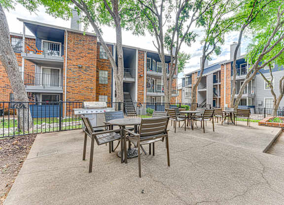 A patio with a table and chairs is surrounded by apartment buildings.