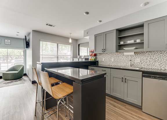 A kitchen with a black countertop and wooden chairs.