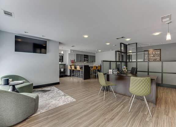 A modern living room with a grey sofa, a green chair, and a wooden floor.