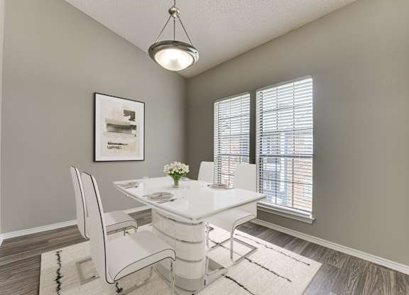 A dining room with a white table and chairs.