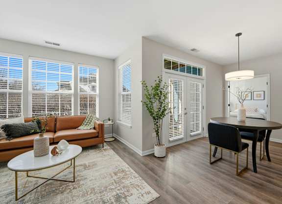 A living room with a brown couch, a coffee table, and a dining table.