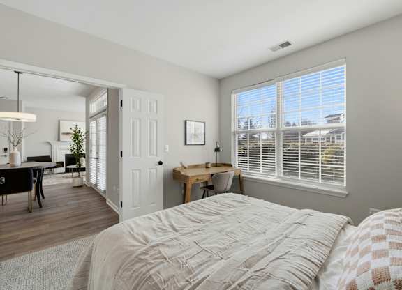 A bedroom with a large bed and a desk with a chair.