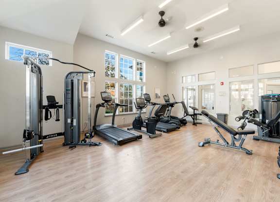 A gym with a variety of equipment including treadmills, weights, and exercise machines.