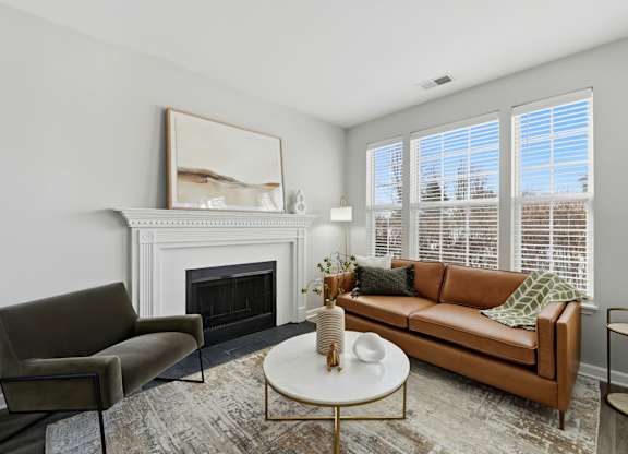 A living room with a fireplace, a couch, a chair, a coffee table, and a painting on the wall.