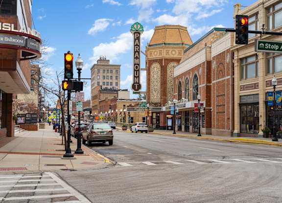 A city street with traffic lights and a Paramount Theatre sign.