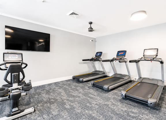A gym with treadmills and a television.