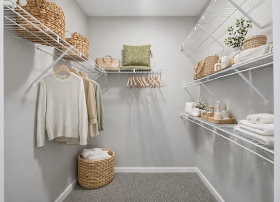 A white closet with clothes and towels.